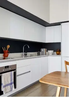  ??  ?? KITCHEN
Simple white units from Commodore Kitchens are set against a matt black splashback for a chic, high-contrast look.
The pale timber of the dining table and chairs prevents it from being too stark