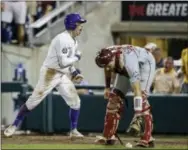  ?? NATI HARNIK — THE ASSOCIATED PRESS ?? LSU’s Cole Freeman, left, celebrates after scoring in the eighth inning as Florida State catcher Cal Raleigh reacts at the College World Series on Saturday.