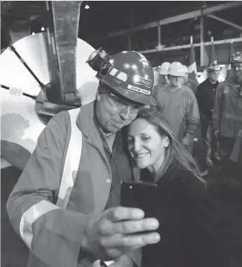  ?? PETER POWER / THE CANADIAN PRESS FILES ?? Global affairs minister Chrystia Freeland, seen taking a picture with a Stelco area manager in Hamilton, Ont., in June, has maintained that the modernizat­ion of NAFTA and the steel and aluminum dispute were separate issues. Yet the new deal shows that is not the case, John Ivison writes.