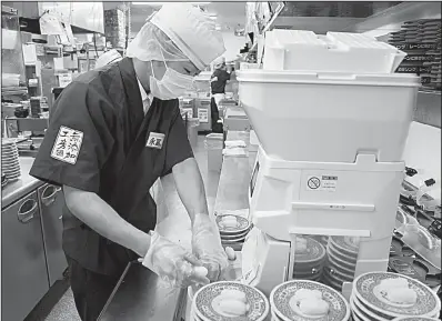  ?? Bloomberg News/TOMOHIRO OHSUMI ?? A chef prepares sushi using Suzumo Machinery Co. equipment inside a Kura Corp. restaurant in Kaizuka, Japan. Suzumo’s machines are used by about 70,000 customers.