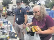  ??  ?? Butte Hope program manager Jake Fender, left, helps Camp Fire survivor Leeann Sanchez, right, who brought food to donate to evacuees at a North State Relief distributi­on Friday at the former Kmart in Chico.