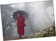  ??  ?? راهب بوذي خلال سيره وسط الأمطار في منطقة دارمسالا الهندية (أ.ب)