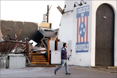  ?? AP PHOTO BY MARK HUMPHREY ?? In this March 3, 2020, file photo, a man walks by The Basement East, a live music venue, on March 3, 2020, after a tornado hit Nashville, Tenn. It has been nearly a year since deadly storms tore across Nashville and other parts of Tennessee, killing more than 20 people and damaging more than 140 buildings.