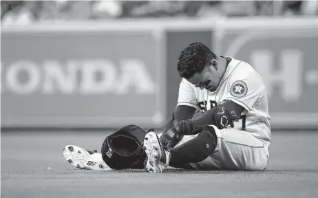  ?? Karen Warren / Staff photograph­er ?? Astros star Jose Altuve sits on the turf after injuring his left hamstring on an infield single in the eighth inning Monday night.