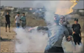  ?? AP/KHALIL HAMRA ?? A Palestinia­n protester on Friday throws back a tear gas canister fired by Israeli soldiers during clashes on the Israeli border with Gaza related to protests against metal detectors Israel installed at a shrine in Jerusalem.