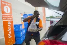  ?? Harrison Hill/ The New York Times ?? Employee Timothy Waters loads a car with groceries in the pickup area of a Walmart in Turnersvil­le, N. J. Store workers are seeing better pay than a generation ago, but there are fewer of them.