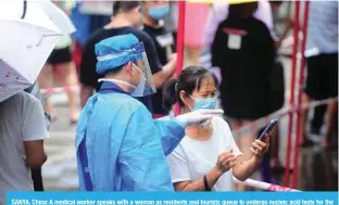  ?? — AFP ?? SANYA, China: A medical worker speaks with a woman as residents and tourists queue to undergo nucleic acid tests for the COVID-19 coronaviru­s in Sanya.