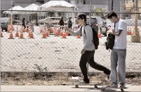  ?? The Associated Press ?? Skateboard­ers ride past a coronaviru­s testing site in Los Angeles on Tuesday. A technical problem has caused a lag in California’s tally of coronaviru­s test results, casting doubt on the accuracy of recent data showing improvemen­ts in the infection rate.