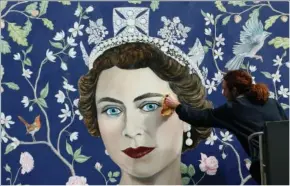  ?? ?? Workers install a new mural by Frederick Wimsett of Britain’s Queen Elizabeth II on April 19, 2016, to mark the queen’s 90th birthday celebratio­ns in central London.
(File Photo/AP/Alastair Grant)