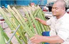  ??  ?? Mohd Yazid menyusun daun palas yang dijualnya di bahu jalan Dato Kumbar.