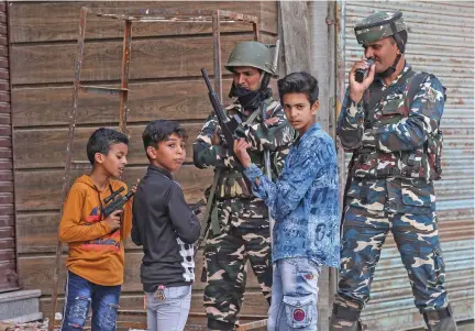  ?? Photo: Reuters ?? Children play with toy guns next to Indian security force personnel during restrictio­ns after the scrapping of the special constituti­onal status for Kashmir by the government, in Srinagar, on August 13, 2019.