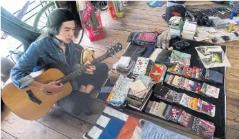  ??  ?? ROMANCE IS DEAD: A man strums a guitar at the once-a-month Old Flames market in Hanoi. Curious customers leaf through old books, love notes, candles and clothes.