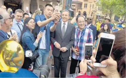  ?? NG HAN GUAN/ASSOCIATED PRESS ?? Disney CEO Bob Iger — center, posing with visitors last year at the Disney Resort in Shanghai, China — has extended his contract by a year.