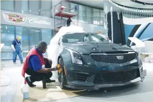  ?? (Rebecca Cook/Reuters) ?? A DETAILER cleans the rims of a 2017 Cadillac ATS vehicle before the start of the North American Internatio­nal Auto Show in Detroit on Saturday.