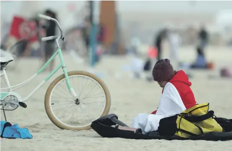  ?? Chris Whiteoak / The National ?? A cyclist clad in hat and sweater takes a break on Kite Beach in Dubai