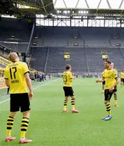  ?? — AP ?? Dortmund’s Erling Haaland (left) celebrates with his teammates — maintainin­g social distance — after scoring the opening goal in their German league match against Schalke 04 in Dortmund, Germany, on Saturday. Dortmund won 4-0.