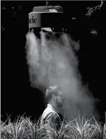  ?? ASSOCIATED PRESS PHOTOS ?? A MAN STANDS UNDER A MISTING MACHINE MONDAY IN TEMPE. The forecast called for a high of 118 on Monday and 120 on Tuesday in Phoenix.