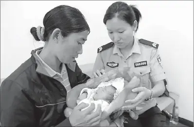  ?? HOU QIGUANG / FOR CHINA DAILY ?? A woman holds a baby who police say she bought in Sichuan province, after they were stopped by police in Xuzhou, Jiangsu province, in early June. Experts in baby traffickin­g said parents who sell their babies should not get their children back.