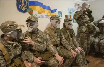  ?? Efrem Lukatsky/Associated Press ?? Cadets practice putting on gas masks during a lesson in a bomb shelter in a cadet lyceum in Kyiv, Ukraine, in June. Writing on the wall reads: “Glory to Ukraine.”