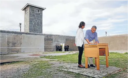  ?? Photo: REUTERS ?? Rememberin­g Africa’s dark past: United States President Barack Obama writes in a guest book as he and wife Michelle tour Robben Island, near Cape Town. Nelson Mandela spent 18 of his 27 years as a political prisoner on Robben Island.