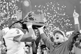  ?? C.B. SCHMELTER/ASSOCIATED PRESS ?? Georgia linebacker Roquan Smith (3) and coach Kirby Smart raise the trophy after Georgia won the SEC championsh­ip game 28-7 over Auburn on Saturday in Atlanta.