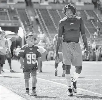  ?? Robert Gauthier Los Angeles Times ?? ESCORTING young fans like Joshua Amaro-Anderson around the field has been a pregame ritual for the Chargers’ Chris McCain throughout his NFL career. “I just do it to give back,” he says. “I love kids.”