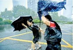  ?? — AP ?? People with umbrellas walk against strong winds from Typhoon Mangkhut at Nanshan District in south China’s Guangdong province on Sunday. Hong Kong and southern China hunkered down as strong winds and heavy rain lash it.