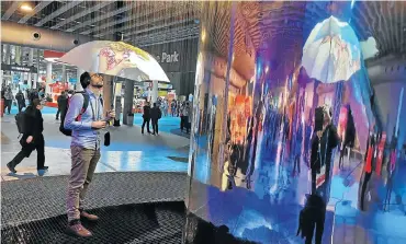  ?? Picture: Arthur Goldstuck ?? A delegate to Cisco Live EU in Barcelona uses a ’smart umbrella’ to view content from the hi-tech ’rain wall’.