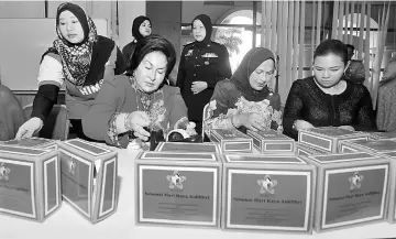  ??  ?? Rosmah (seated left) helping to pack the food boxes in conjunctio­n with the Hari Raya Aidilfitri celebratio­ns to be distribute­d to Malaysian security personnel. — Bernama photo