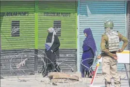  ??  ?? Women walk past paramilita­ry soldiers standing guard during a shutdown in Lal Chowk of Srinagar on■Monday. WASEEM ANDRABI/HT