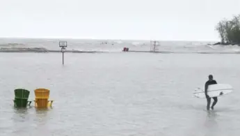  ?? STEVE RUSSELL/TORONTO STAR ?? Mike Langlois wades through the flooded shore after a surf in Lake Ontario.