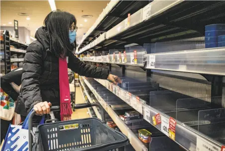  ?? Anthony Kwan / Getty Images ?? A customer wears a face mask to protect against the new virus while shopping at a grocery store in Hong Kong.