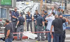  ?? JACK GUEZ, AFP/GETTY IMAGES ?? Israeli forces inspect the body of a Palestinia­n man who was shot dead after carrying out a stabbing attack on an Israeli soldier and three passersby in Tel Aviv on Thursday.