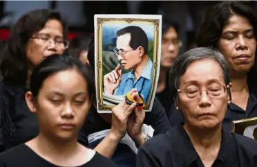  ??  ?? Sombre affair: In this file photo dated Oct 13, 2017, mourners hold a portrait of the late King Bhumibol Adulyadej during a moment of silence at Siriraj Hospital where he died a year earlier in Bangkok, Thailand. —AP