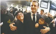  ?? YOAN VALAT / POOL VIA REUTERS FILES ?? President Emmanuel Macron hugs staff at the new Café Joyeux coffee shop in Paris which employs people with
Down syndrome and other cognitive disabiliti­es.