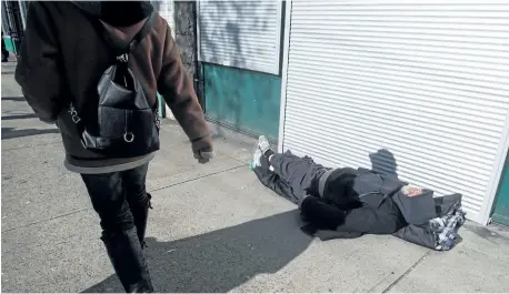  ?? THE CANADIAN PRESS FILES ?? A woman walks past a man sleeping on the street in the Downtown Eastside of Vancouver, B.C., in February. Cities struggling to house their homeless are asking the federal Liberals to rethink the government’s cornerston­e homelessne­ss program.