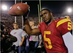  ?? Associated Press file photo ?? ■ Southern California tail back Reggie Bush walks off the field holding the game ball on Nov. 19. 2005, after the Trojans defeated Fresno State, 50-42, at the Los Angeles Coliseum. USC President Carol Folt wrote in a letter to Bush on Wednesday that he could now “be afforded the privileges and courtesies extended to all Trojan football alums.”