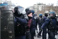  ?? The Associated Press ?? ■ A bleeding man is detained by police officers during a demonstrat­ion Tuesday in Paris. Demonstrat­ors were marching across France on Tuesday in a new round of protests and strikes against the government’s plan to raise the retirement age to 64.