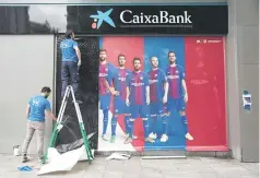  ??  ?? Two men put up a new poster outside the Camp Nou Stadium in Barcelona. — AFP photo