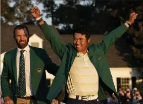  ?? DAVID J. PHILLIP - THE ASSOCIATED PRESS ?? FILE - In this Sunday, April 11, 2021 file photo, Hideki Matsuyama, of Japan, puts on the champion’s green jacket after winning the Masters golf tournament as Dustin Johnson watches in Augusta, Ga.