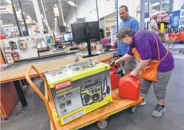  ?? Ken Blevins / Associated Press ?? Delma Hewitt checks out Al Lombardi as he purchases a generator at Home Depot in Monkey Junction, N.C. Backup power generators range in cost from hundreds to thousands of dollars.