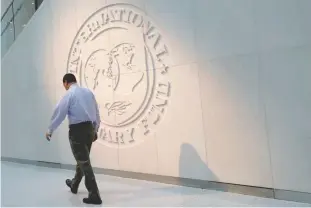  ?? — Reuters file photo ?? A man walks past the IMF logo at HQ in Washington.