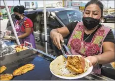  ??  ?? ADELA RUIZ, right, prepares tacos de chile relleno at the cookout, which allows Oaxacan vendors in L.A. to promote their businesses.