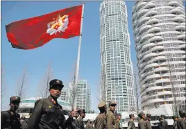  ?? Wong Maye-e ?? The Associated Press North Korean soldiers carry the Korean People’s Army flag as they walk past residentia­l buildings along Ryomyong Street in Pyongyang, North Korea.