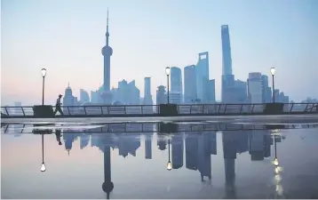  ??  ?? A security guard walks on the bund in front of the financial district of Pudong in Shanghai, China. — Reuters photo