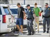  ?? TRAVIS SPRADLING / THE ADVOCATE ?? Zachary Hall (left) and Sean Pennison (second from right) are escorted by Louisiana State University police officers Wednesday after being booked on charges of hazing in a pledge’s death.