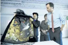  ?? JUSTIN TANG/THE CANADIAN PRESS ?? Eric Chan, left, faculty at the Applied Research and Innovation Centre at Algonquin College, shows Minister of Finance Bill Morneau a jacket featuring his original art that he collaborat­ed on with Canada Goose, before a discussion on skills and...