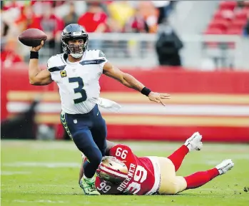  ?? JOHN HEFTI/THE ASSOCIATED PRESS ?? Seattle Seahawks quarterbac­k Russell Wilson throws while being tackled by San Francisco’s DeForest Buckner during the first half in Santa Clara Sunday afternoon.