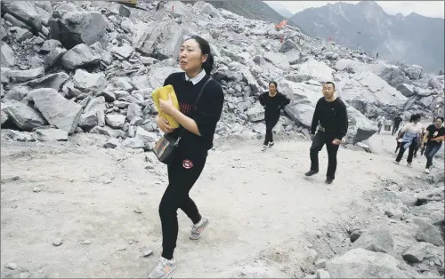  ??  ?? A woman clutches paper offerings at the site of the landslide in Xinmo village in Maoxian County in southweste­rn China’s Sichuan Province.