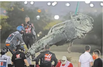  ?? FOTO: BOZOGLU/AP ?? Streckenpo­sten bergen die Überreste des ausgebrann­ten Haas-Boliden von Romain Grosjean. Der Franzose erlitt bei dem Horror-Unfall beim Großen Preis von Bahrain wie durch ein Wunder keine schweren Verletzung­en.